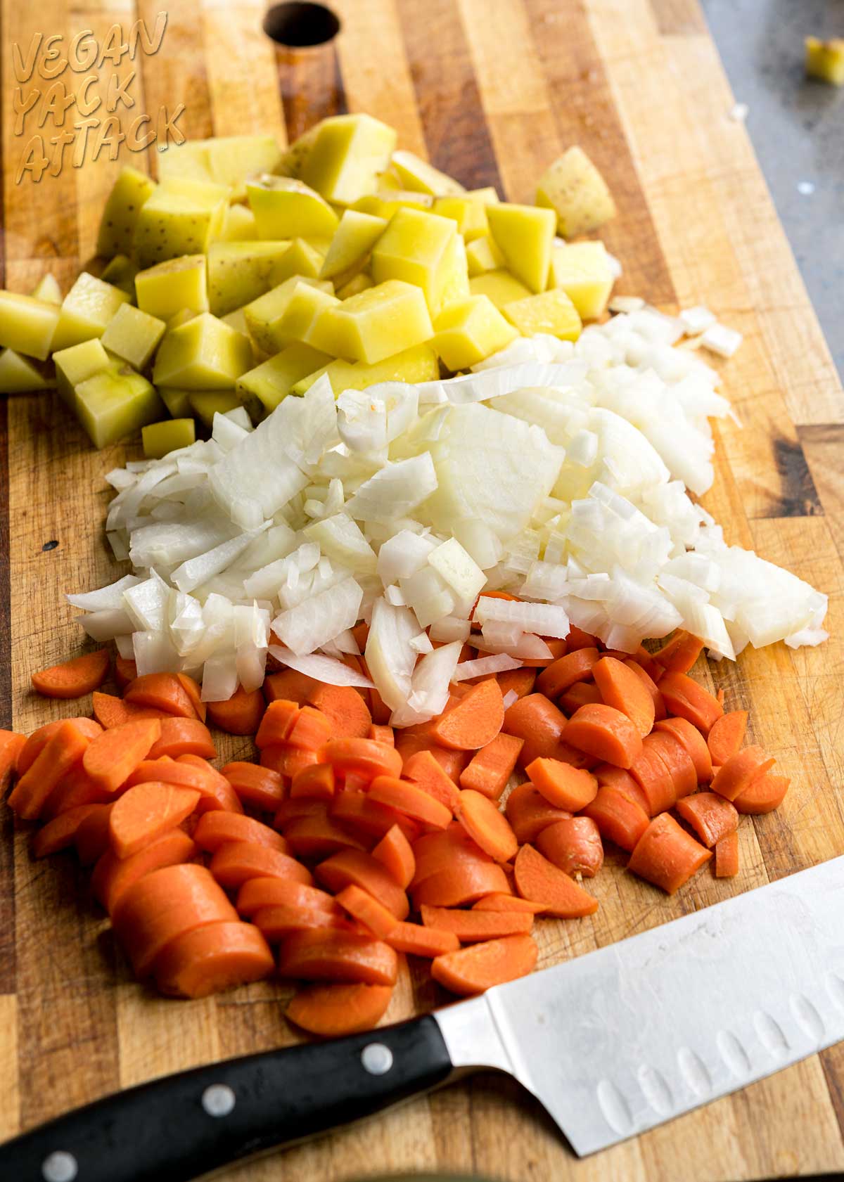 chopped carrots, onion, and potato on a cutting board