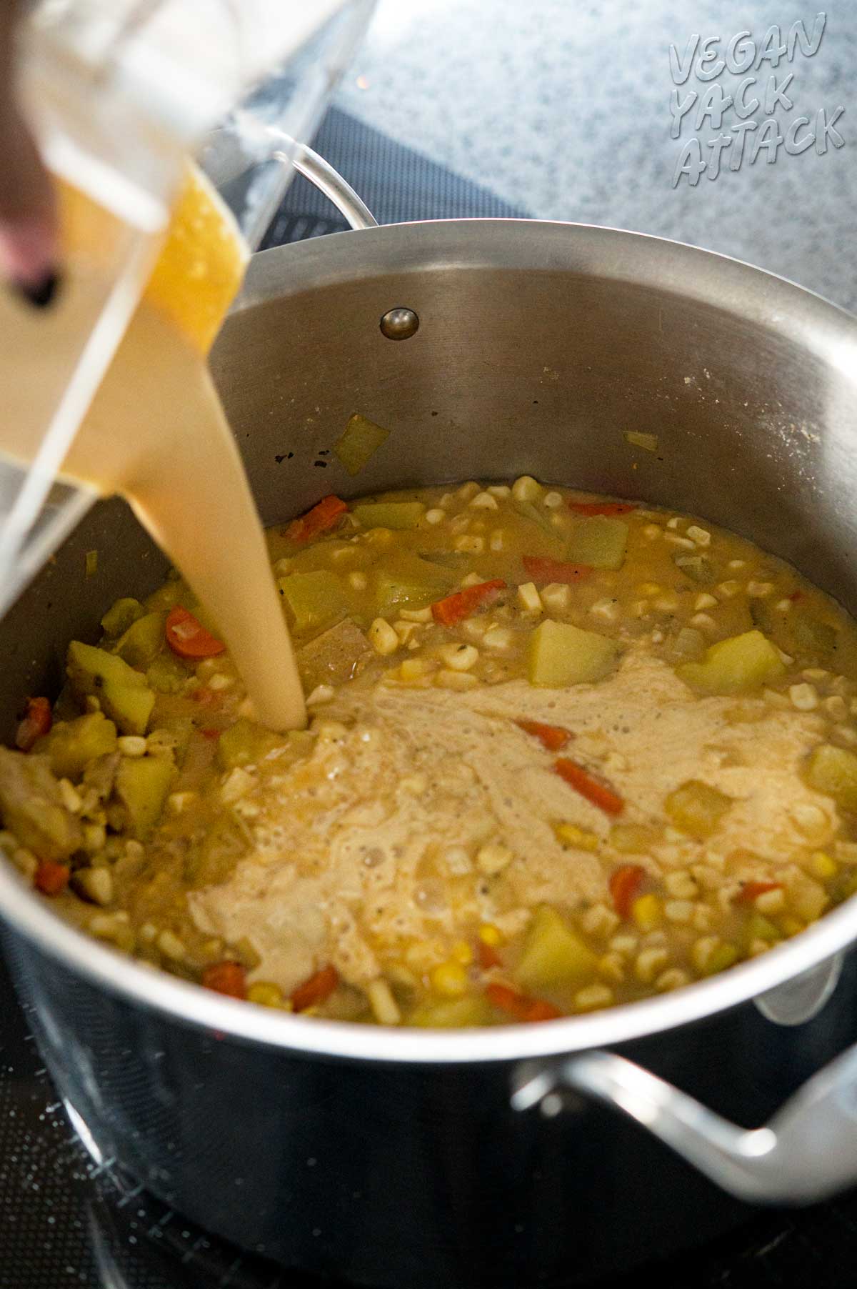 cream being poured into a pot of veggie soup