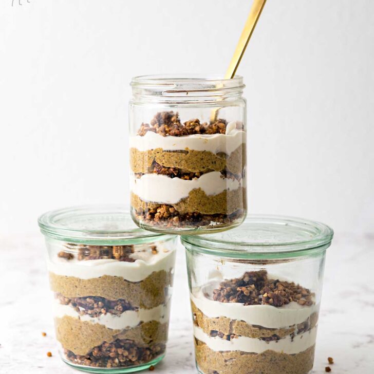 three jars of pumpkin pudding parfait stacked together on a marble table top