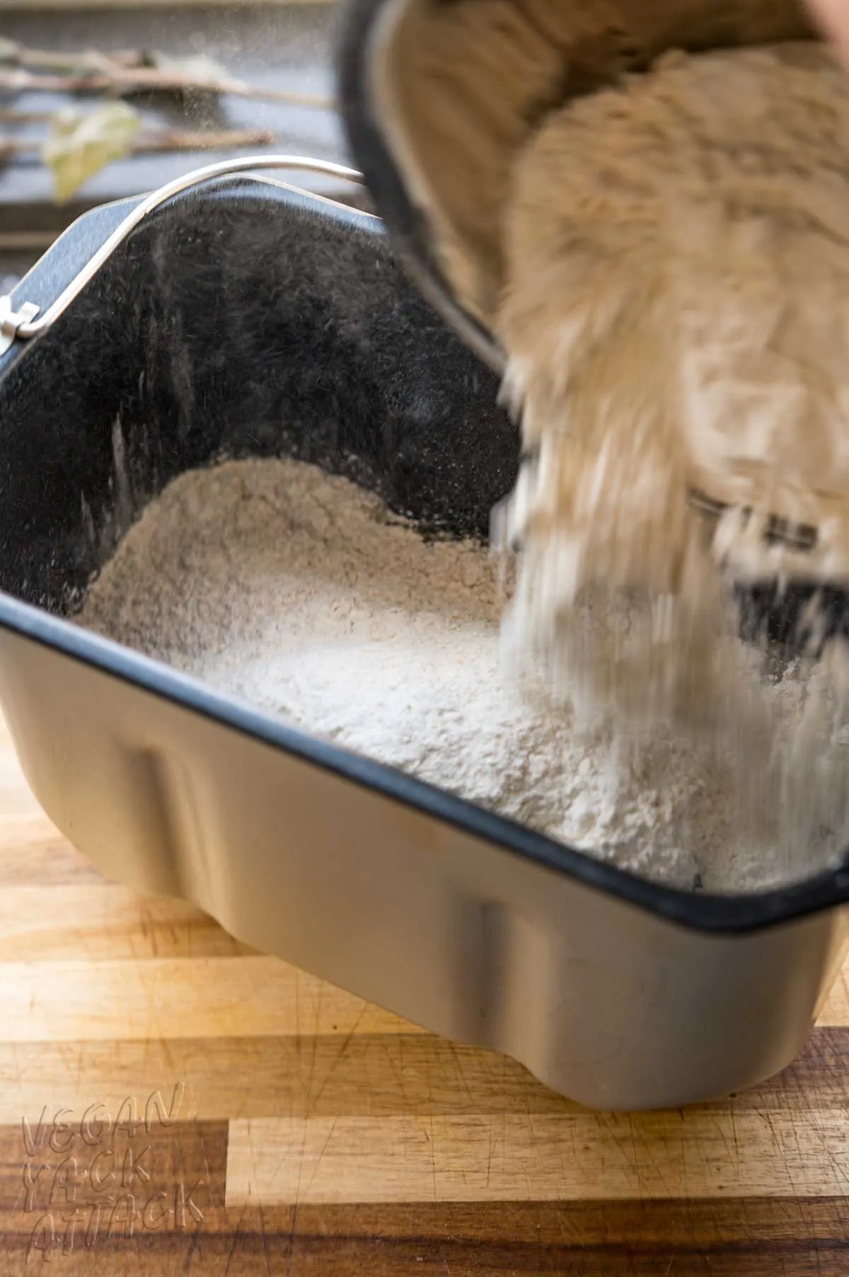 flour being added to bread machine pan