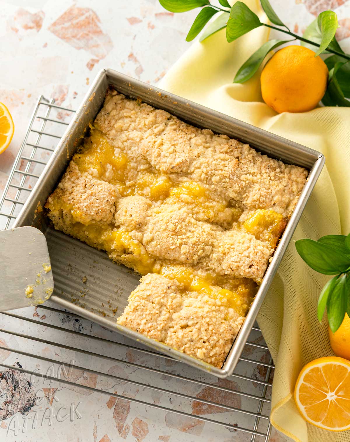 table spread of cut coffee cake in a baking pan with lemons and yellow linen