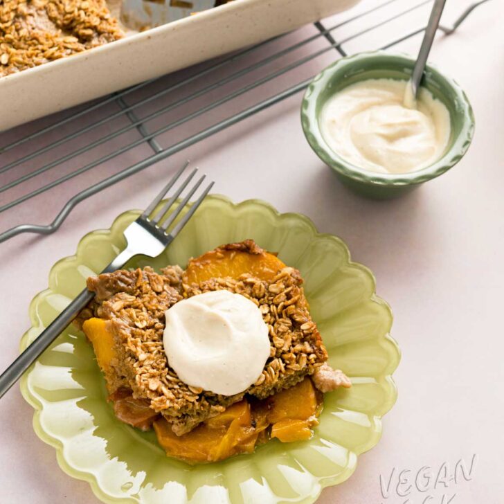 piece of peach cobbler baked oatmeal on a green plate with a small bowl of yogurt