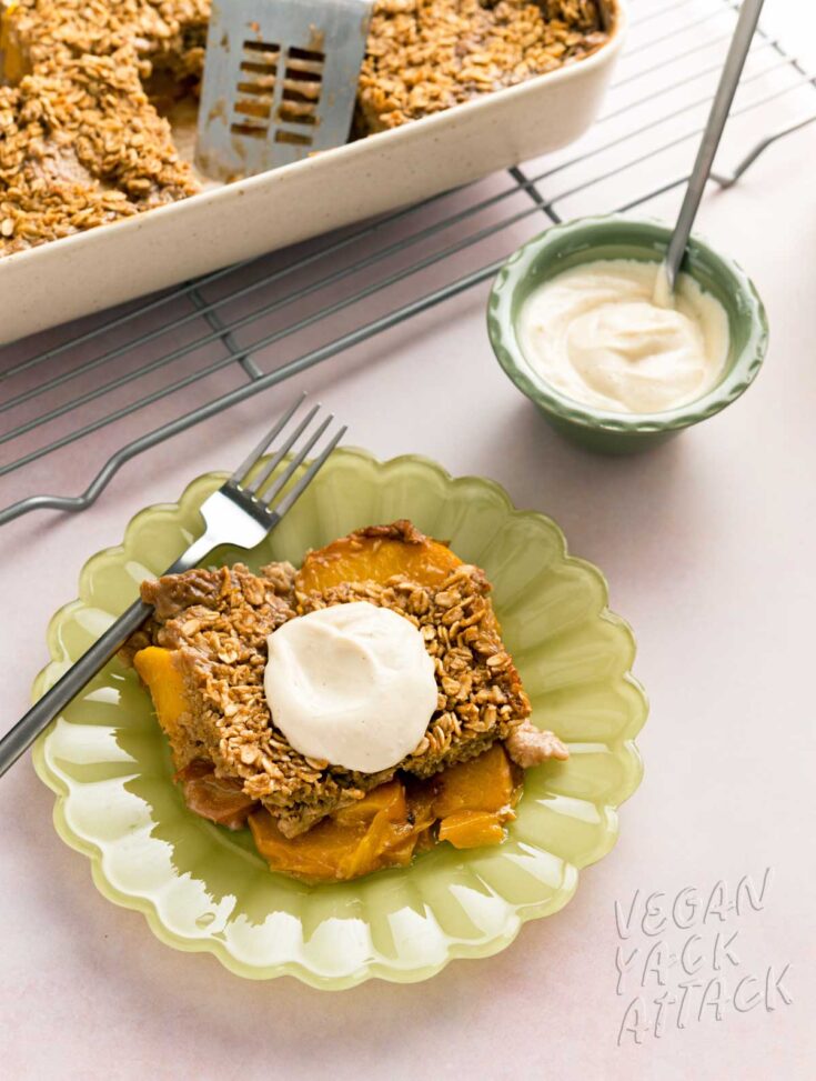 piece of peach cobbler baked oatmeal on a green plate with a small bowl of yogurt