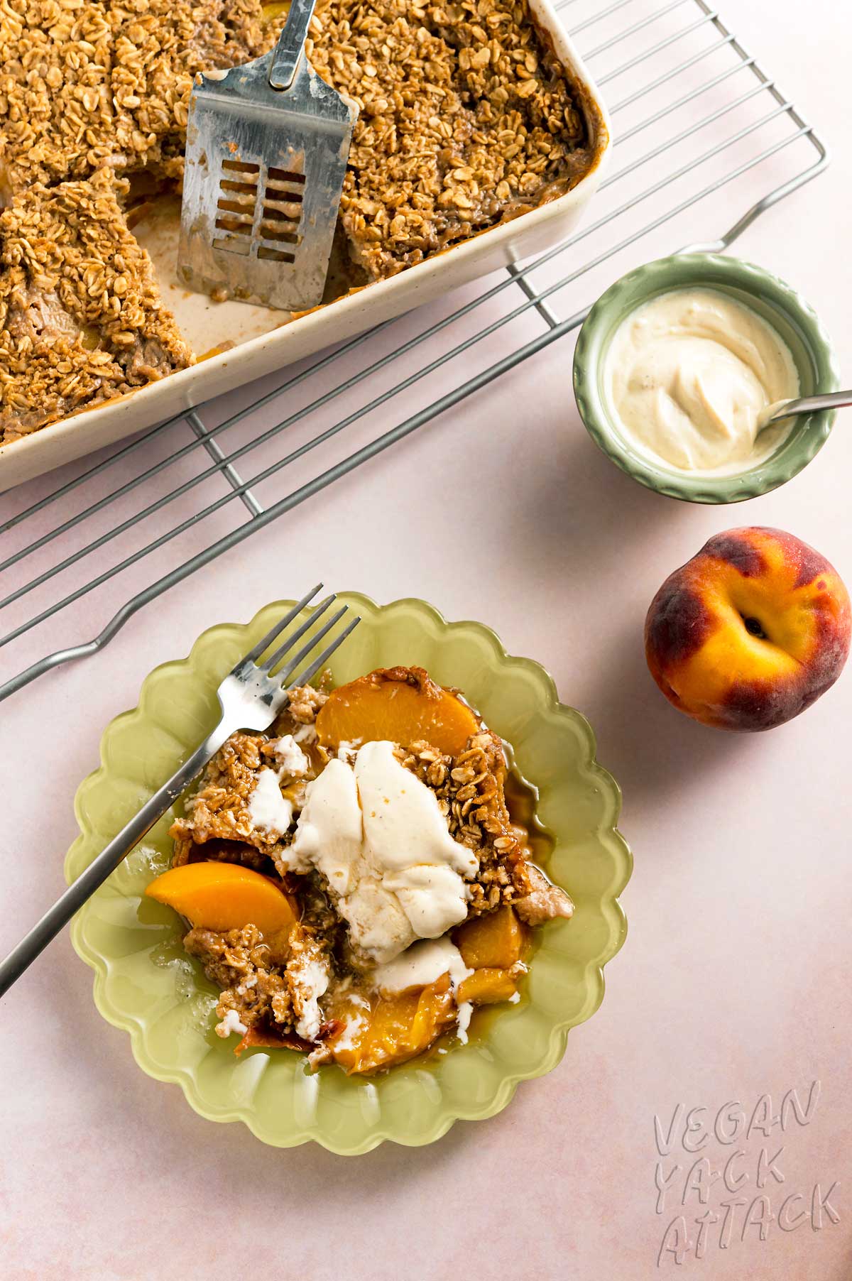 piece of peach cobbler baked oatmeal on a green plate with a small bowl of yogurt