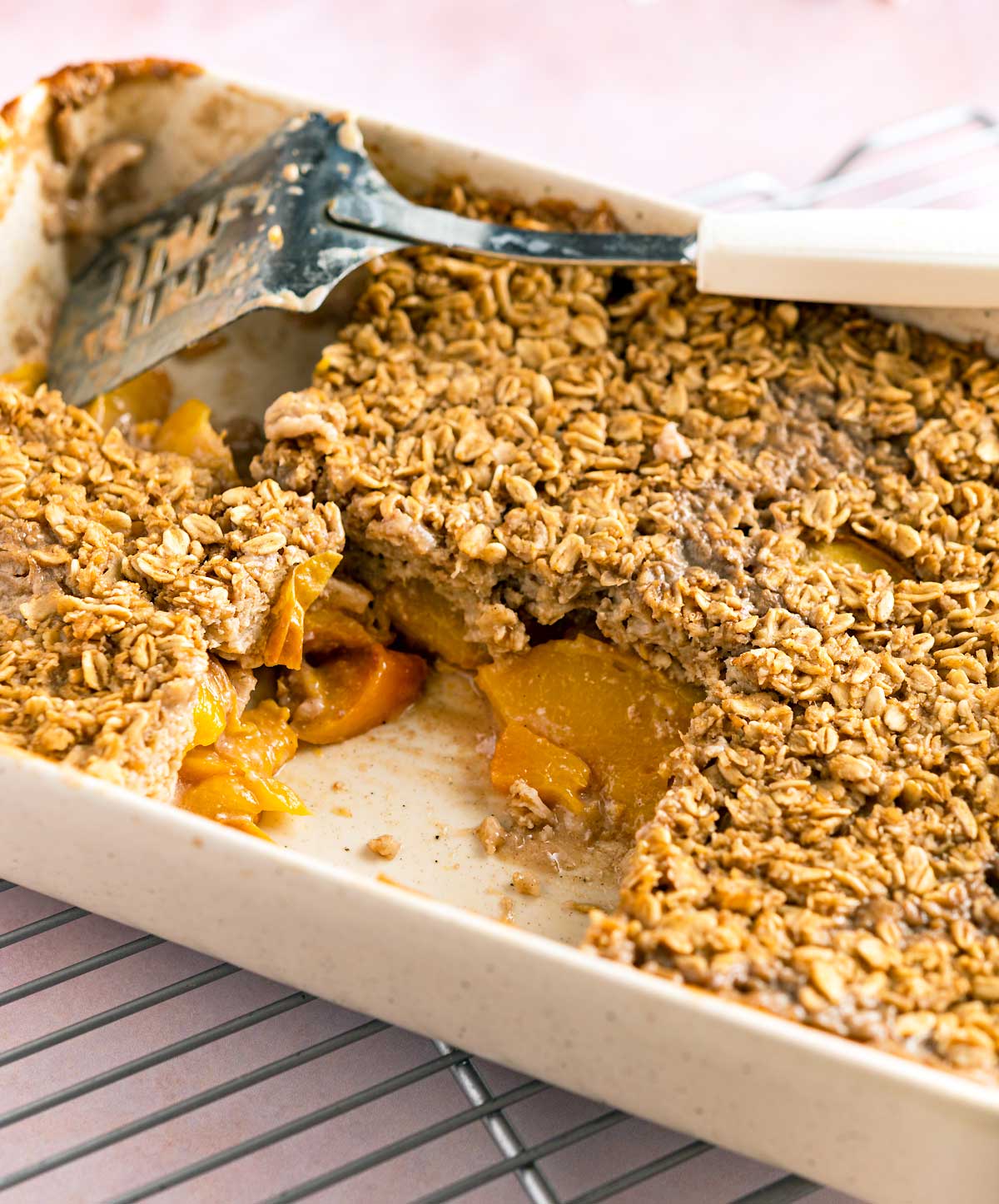 casserole dish of baked peach cobbler oatmeal with some pieces cut out of it